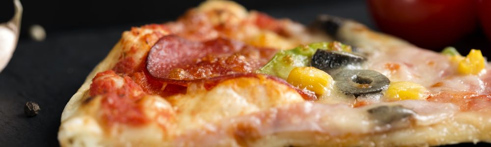 Slice of Italian Capriciosa pizza on dark slate